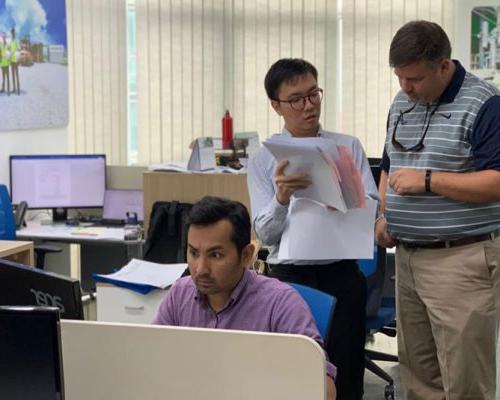 澳门足彩app employees discussing project documents in the Malaysia office